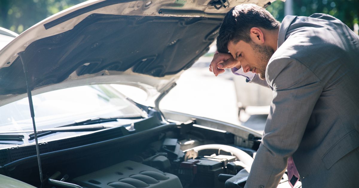 Handsome man looking at his car engine after a vehicle breakdown