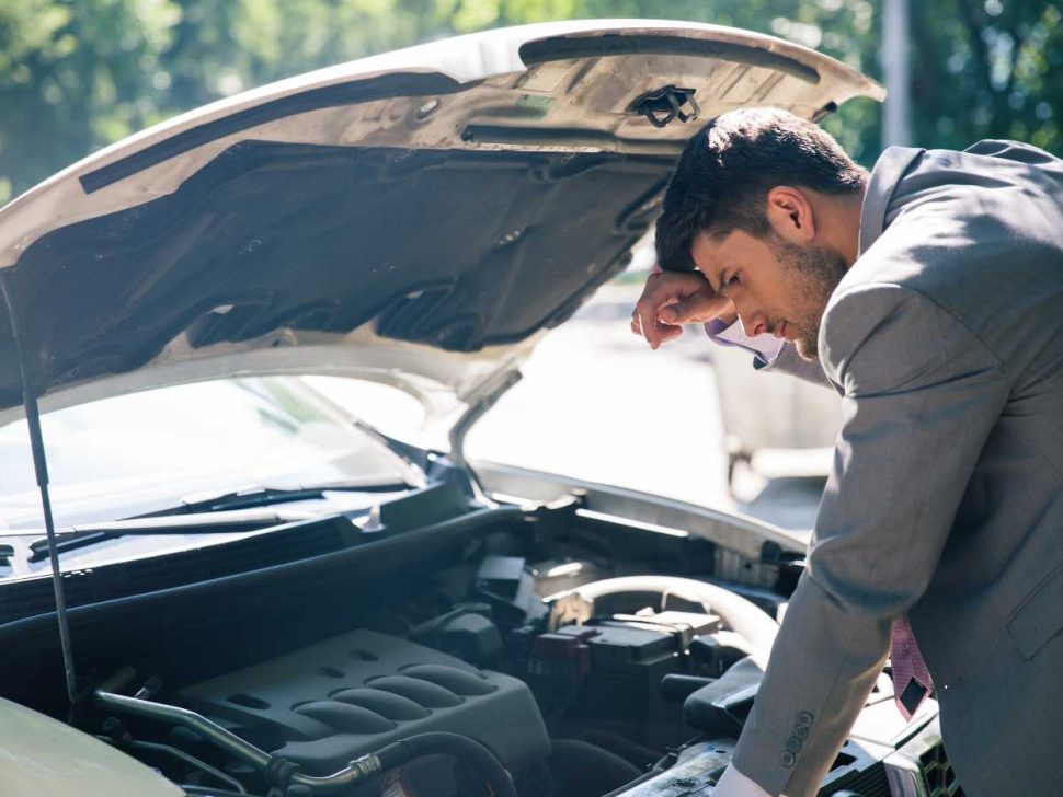 Handsome man looking at his car engine after a vehicle breakdown